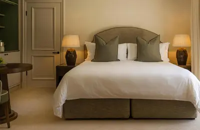 a bedroom with a large bed with white sheets and pillows at Maison Cabrière Boutique Hotel in Franschhoek