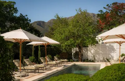 a swimming pool with umbrellas and chairs and a swimming pool at Maison Cabrière Boutique Hotel in Franschhoek
