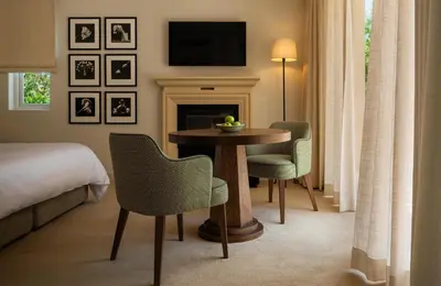 a hotel room with a table and chairs and a television at Maison Cabrière Boutique Hotel in Franschhoek