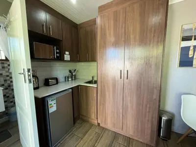 a small kitchen with wooden cabinets and a refrigerator at Panorama Self Catering in Panorama