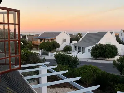 a row of houses with a sunset in the background at Renovated Fishermans Cottage in Hermanus