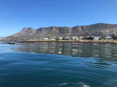 a body of water with houses and mountains in the background at Renovated Fishermans Cottage in Hermanus