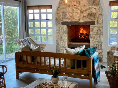 a living room with a stone fireplace and a couch at Renovated Fishermans Cottage in Hermanus