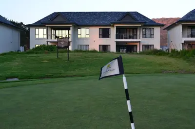 a flag on a putting green in front of a house at Pearl Valley Suites in Simondium