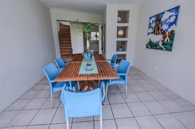 a dining room with a wooden table and blue chairs at Lamabeach city farm in Cape Town