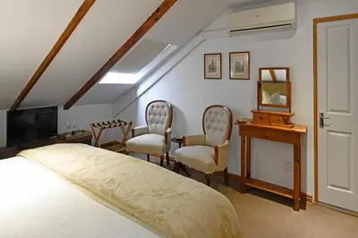 a bedroom with a bed and two chairs and a television at Centre-Ville Guest House in Franschhoek