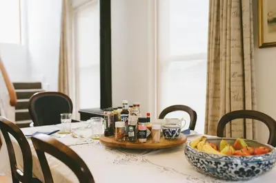 a table with a bowl of fruit and a tray of condiments at The Victorian Goose in Cape Town