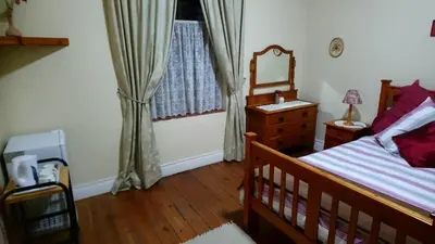 a bedroom with a bed and a dresser and a window at Welterusten Guesthouse in Strand
