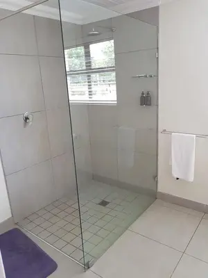 a shower with a glass door in a bathroom at Paddabult Self Catering Cottages in Paarl
