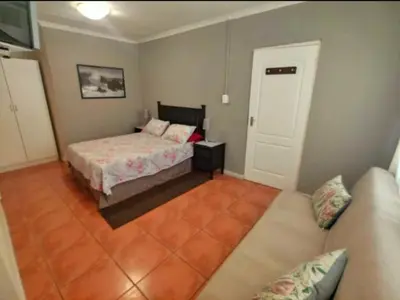 a small bedroom with a bed and a couch at N-One Self Catering in Goodwood