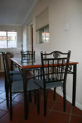 a dining room table with two chairs and a table and chairsktop at N-One Self Catering in Goodwood