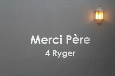 a light on a wall with the words merci per at Merci Pére in Gordonʼs Bay