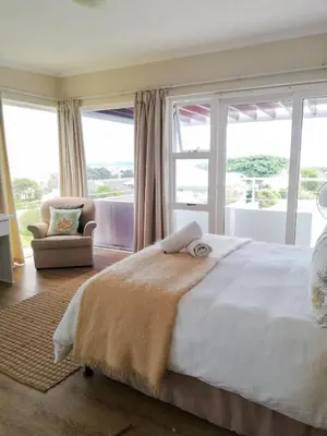 a bedroom with a large bed with a large window at Akwa in Hermanus