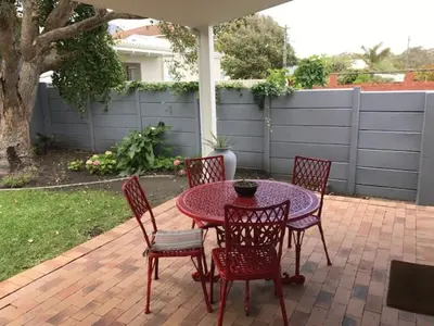 a table with four chairs and a table with an umbrella at Akwa in Hermanus