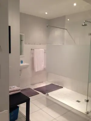 a bathroom with a glass shower and a sink at The Palm in Pinelands in Cape Town