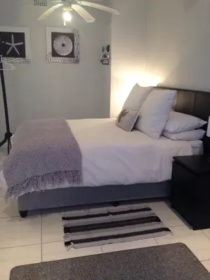 a bedroom with a bed with white sheets and pillows at The Palm in Pinelands in Cape Town
