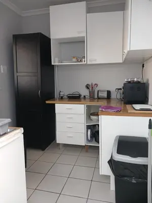 a kitchen with white cabinets and a black door at The Palm in Pinelands in Cape Town