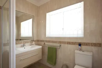 a bathroom with a sink and a toilet and a mirror at Somerset West Self Catering Vacation Rental - Experience the Best of Cape Town - Wine, Golf, Sea in Somerset West