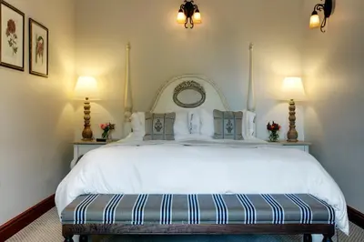 a bedroom with a large white bed with two lamps at Coopmanhuijs Boutique Hotel & Spa in Stellenbosch