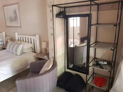a bedroom with a bed and a mirror and a chair at The Fairway in Cape Town
