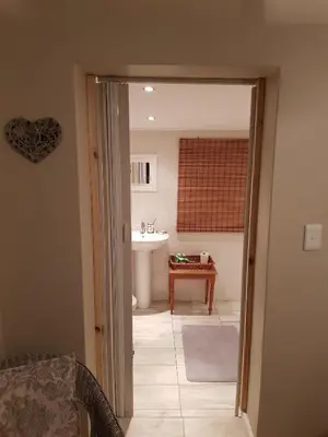 a bathroom with a sink and a door leading into a room at The Fairway in Cape Town