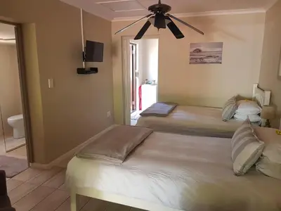 a bedroom with two beds and a ceiling fan at The Fairway in Cape Town