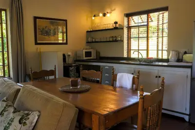 a kitchen with a wooden table and a dining room at Zebra Cottage and Lodge in Stellenbosch
