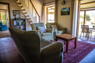 a living room with two chairs and a table at Zebra Cottage and Lodge in Stellenbosch