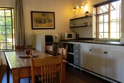 a kitchen with a dining table and a kitchen with a microwave at Zebra Cottage and Lodge in Stellenbosch
