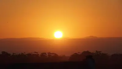 an orange sunset with the sun in the sky at Wind-Rose Guest House in Gordonʼs Bay