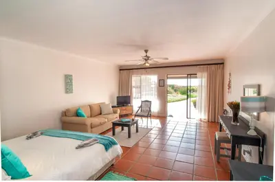 a bedroom with a bed and a living room at Wind-Rose Guest House in Gordonʼs Bay
