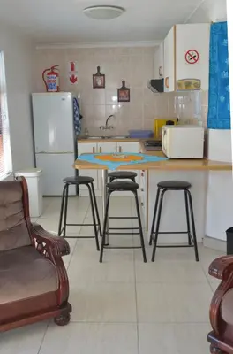 a kitchen with a table and three stools in it at De Helling Self Catering in Brackenfell