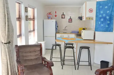 a kitchen with a table and two bar stools at De Helling Self Catering in Brackenfell