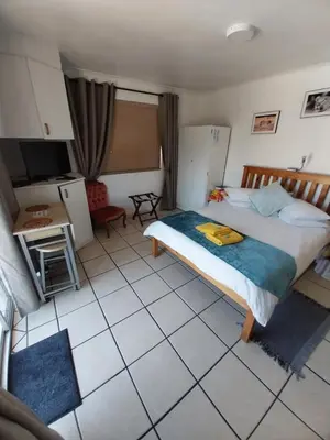 a bedroom with a bed and a tiled floor at De Helling Self Catering in Brackenfell