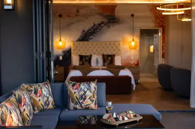a living room with a blue couch and a bed at Kunjani Villas & Wines in Stellenbosch