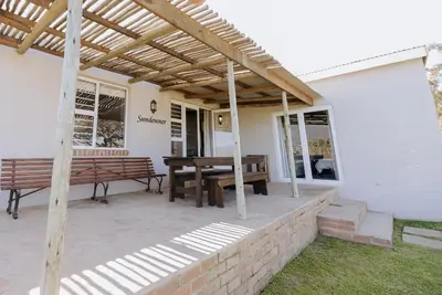 a patio with a wooden pergola and a wooden bench at Dennehof Farm Guesthouse in Villiersdorp