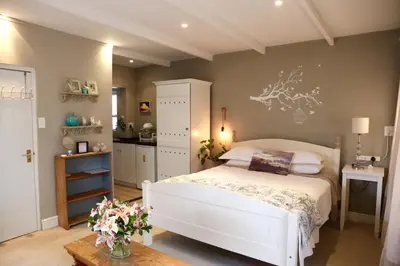 a bedroom with a white bed and a table at The Birdhouse in Cape Town