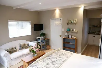 a living room with a white bed and a couch at The Birdhouse in Cape Town