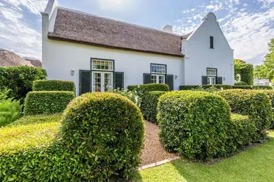 a white house with green hedges in front of it at Van der Stel Manor in Stellenbosch
