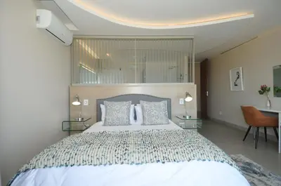 a bedroom with a large white bed and a desk at 7 on Marine in Hermanus