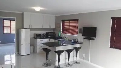 a kitchen with a counter with stools and a refrigerator at Bergsig Selfcatering in Gordonʼs Bay