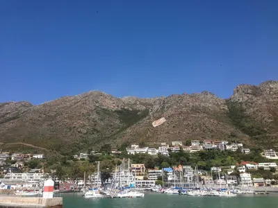 a group of boats docked in a harbor with mountains at Bergsig Selfcatering in Gordonʼs Bay