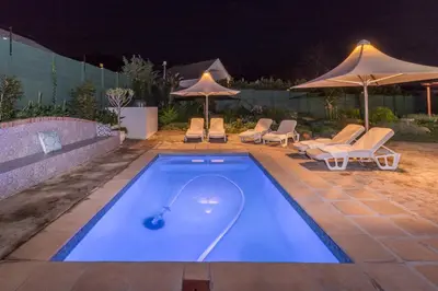 a swimming pool with chairs and umbrellas at night at Waterstone Lodge in Somerset West