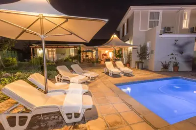 a swimming pool with lounge chairs and an umbrella at Waterstone Lodge in Somerset West