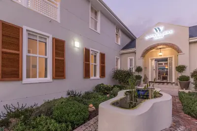 a white house with a courtyard in front of it at Waterstone Lodge in Somerset West