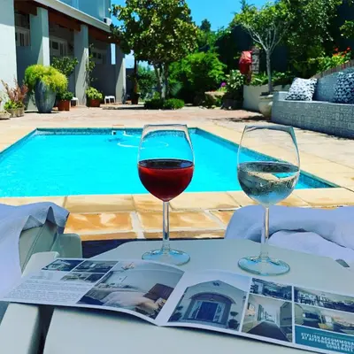 two glasses of wine sitting on a table near a pool at Waterstone Lodge in Somerset West
