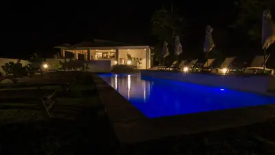 a swimming pool at night with blue illumination at Klein Waterval Riverside Lodge in Franschhoek