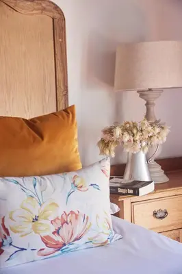 a bed with a pillow and a lamp on a night stand at Klein Waterval Riverside Lodge in Franschhoek
