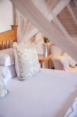 a white bed with a pillow and a table at Klein Waterval Riverside Lodge in Franschhoek