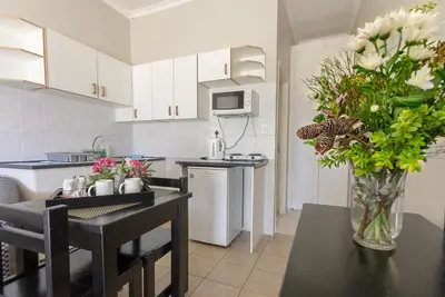 a kitchen with a vase of flowers on a table at Kingfisher Hollow in Gordonʼs Bay